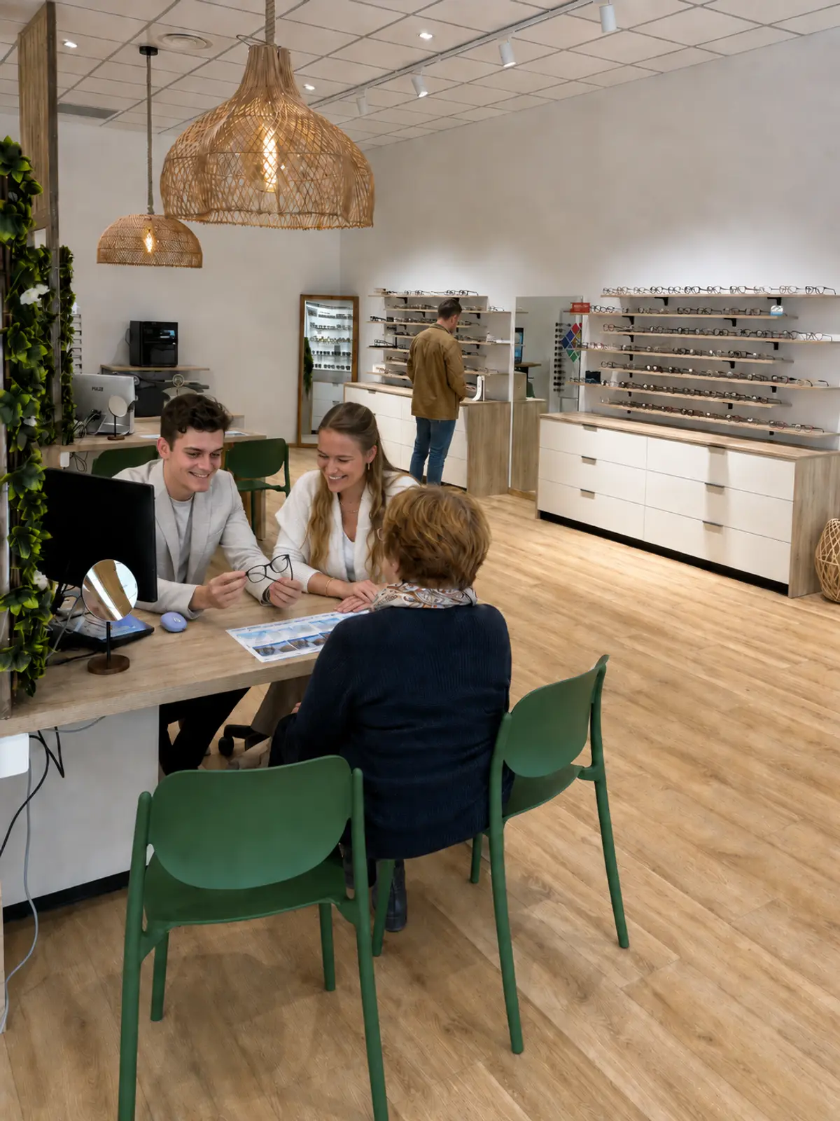 Deux opticiens conseillent une cliente à la table de vente, devant les montures.